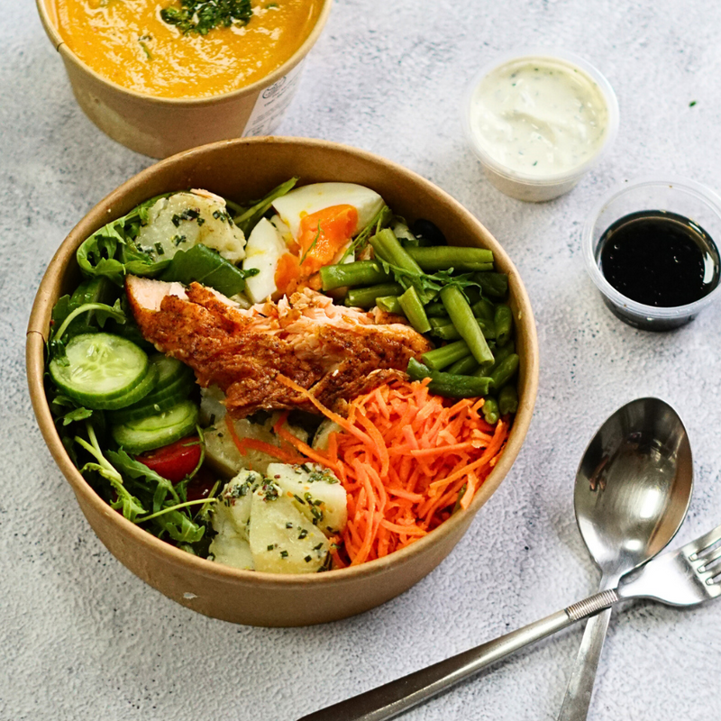 Bowl of salad with a side of soup on a light gray surface